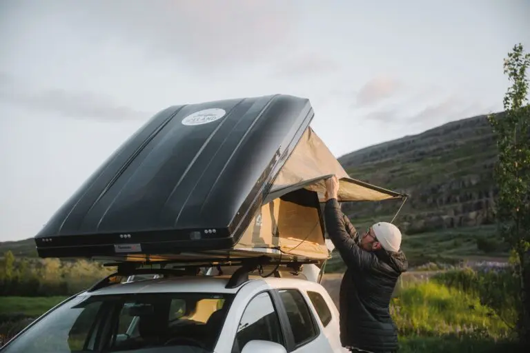 man setting up a rooftop tent on a car in Iceland