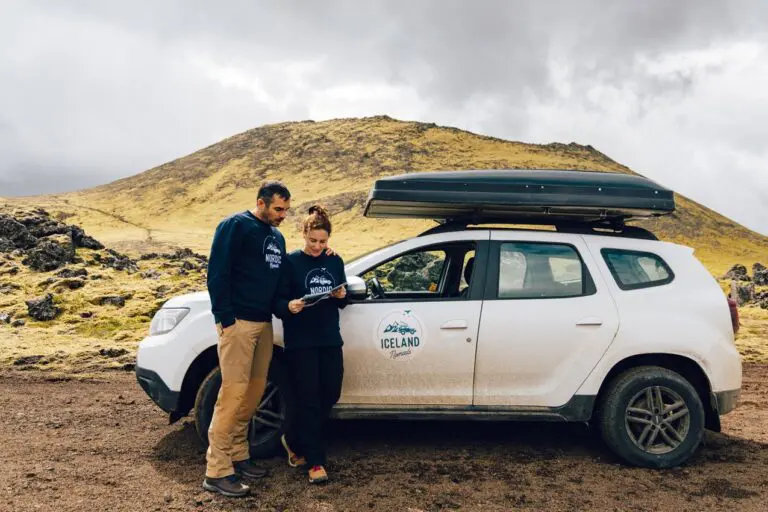 couple checking map next to car in Icelandic landscape