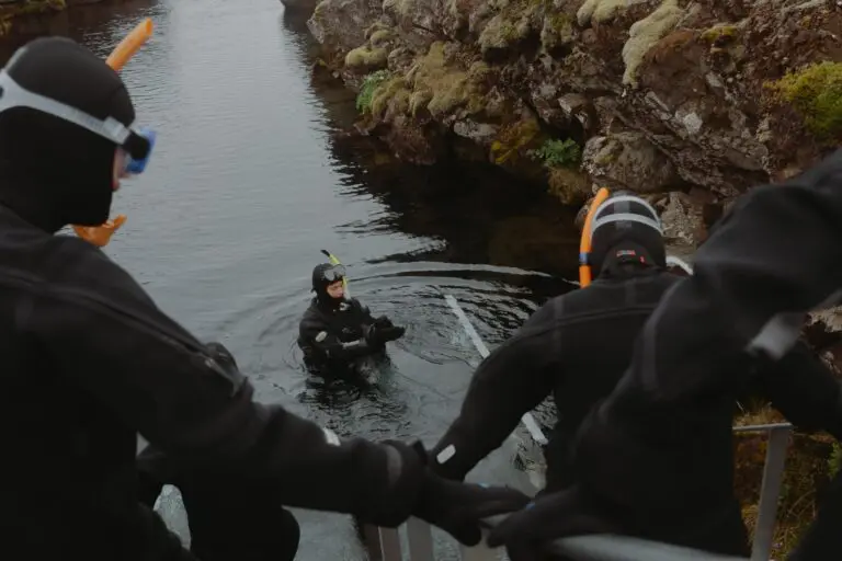 people in dry suits preparing for snorkeling in a river