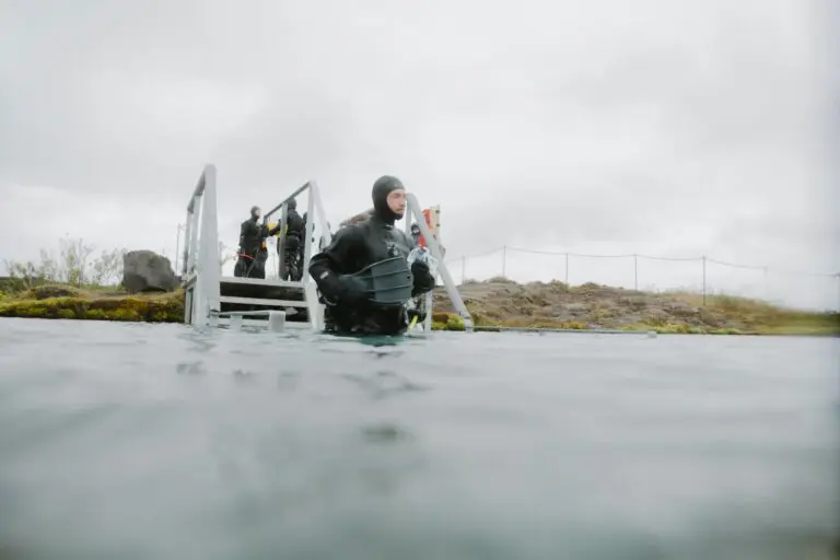 person in dry suit entering cold water for snorkeling or diving