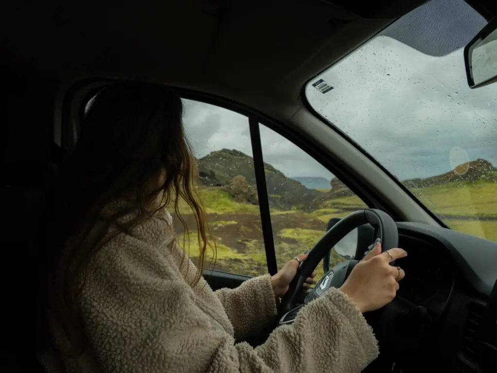 person driving through a green, rugged landscape in Iceland
