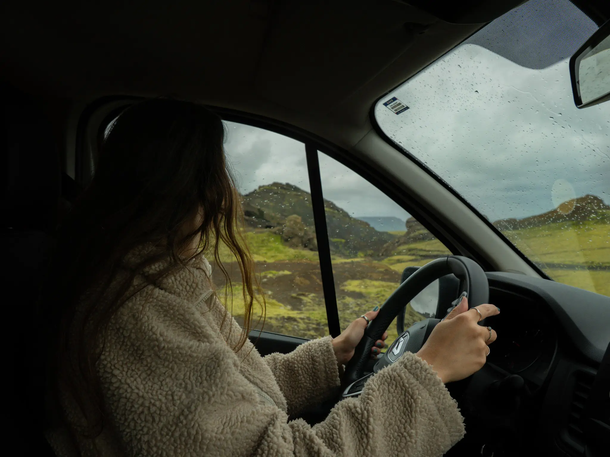 person driving through a green, rugged landscape in Iceland