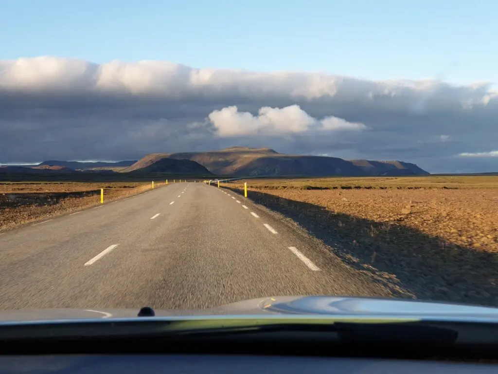empty road through Icelandic landscape under dramatic sky