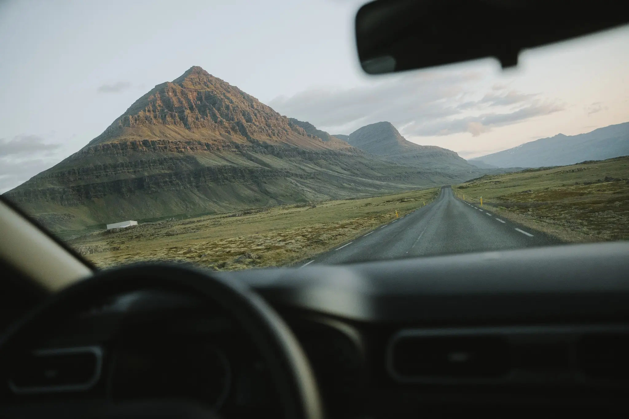 driving through icelandic landscape with mountains and long road