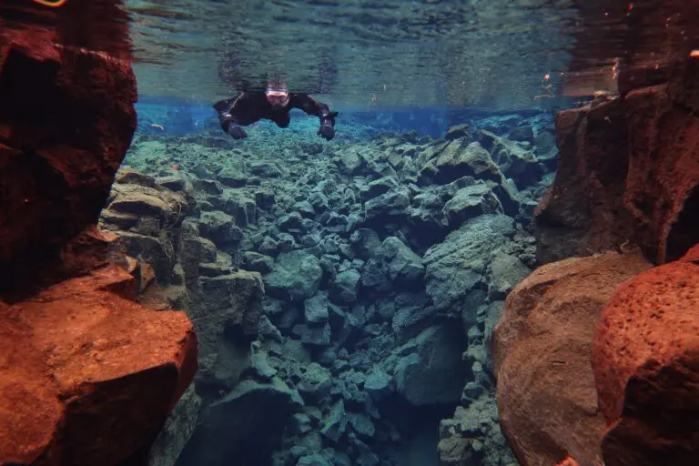 snorkeler in clear blue water between tectonic plates in Iceland