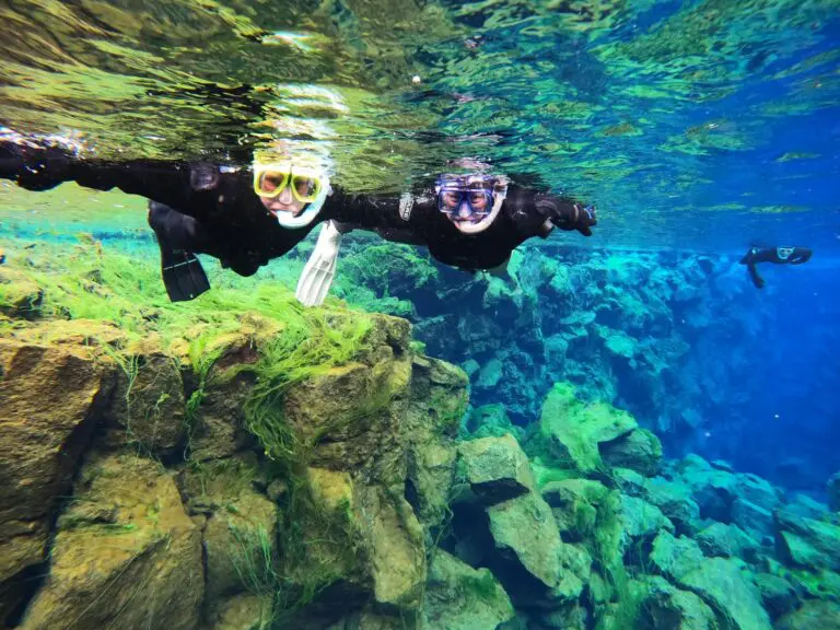 two people snorkeling in clear blue water in Iceland