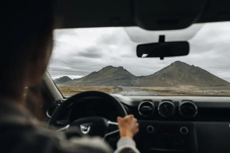 driving through icelandic landscape with mountains under cloudy sky