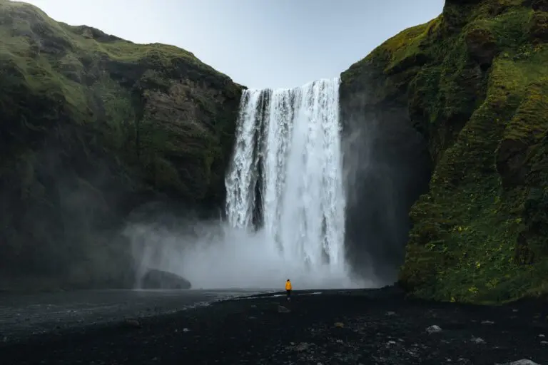 person in yellow jacket at Skogafoss waterfall in Iceland