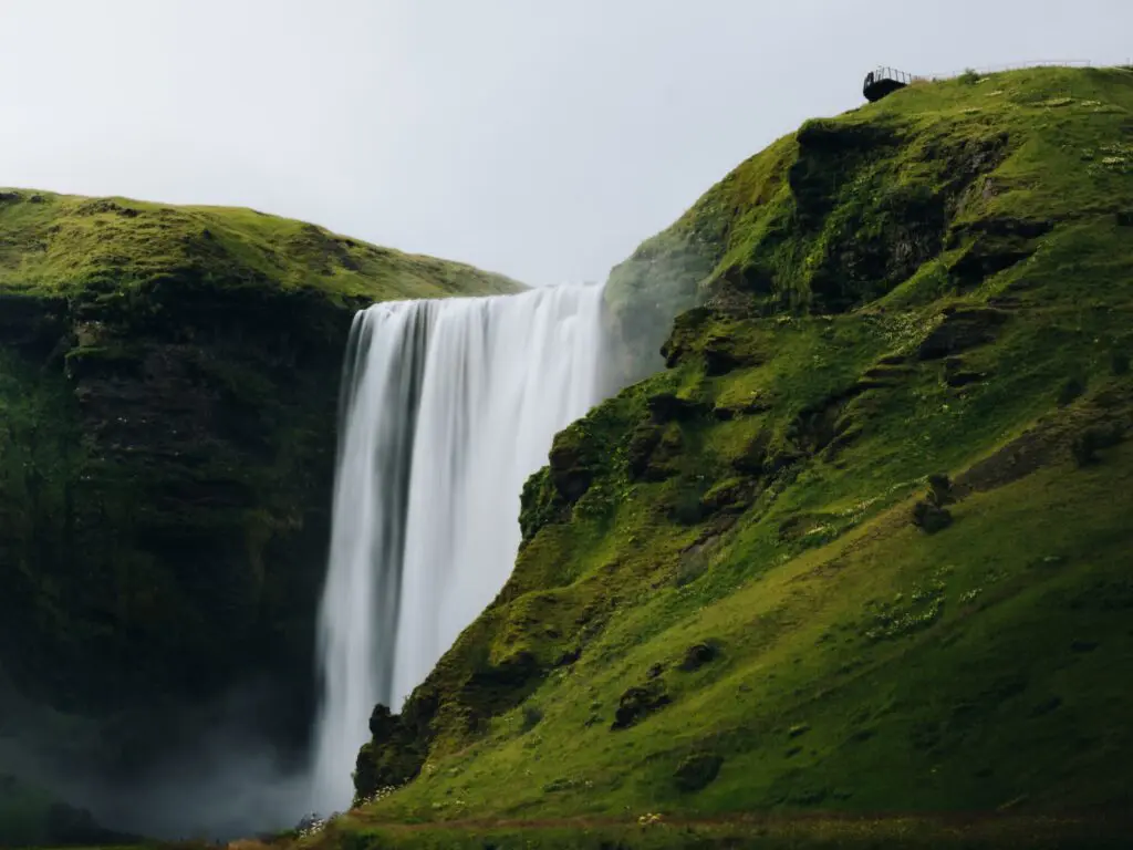 long exposure waterfall cascading down green hills in Iceland