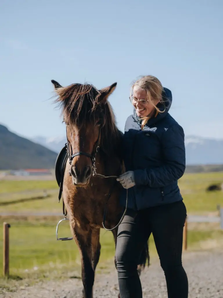 woman smiling next to a brown Icelandic horse