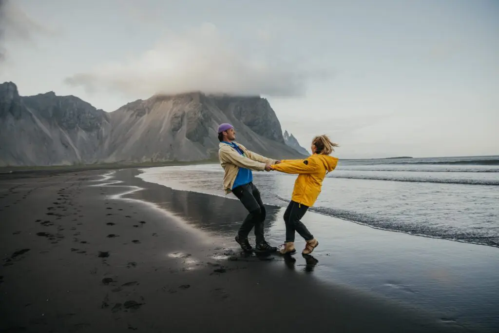 couple holding hands on black sand beach in Iceland