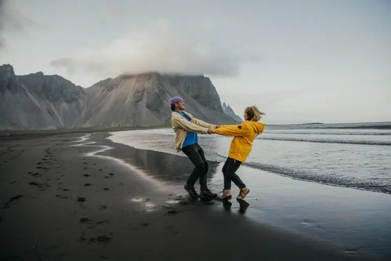 couple holding hands on black sand beach in Iceland