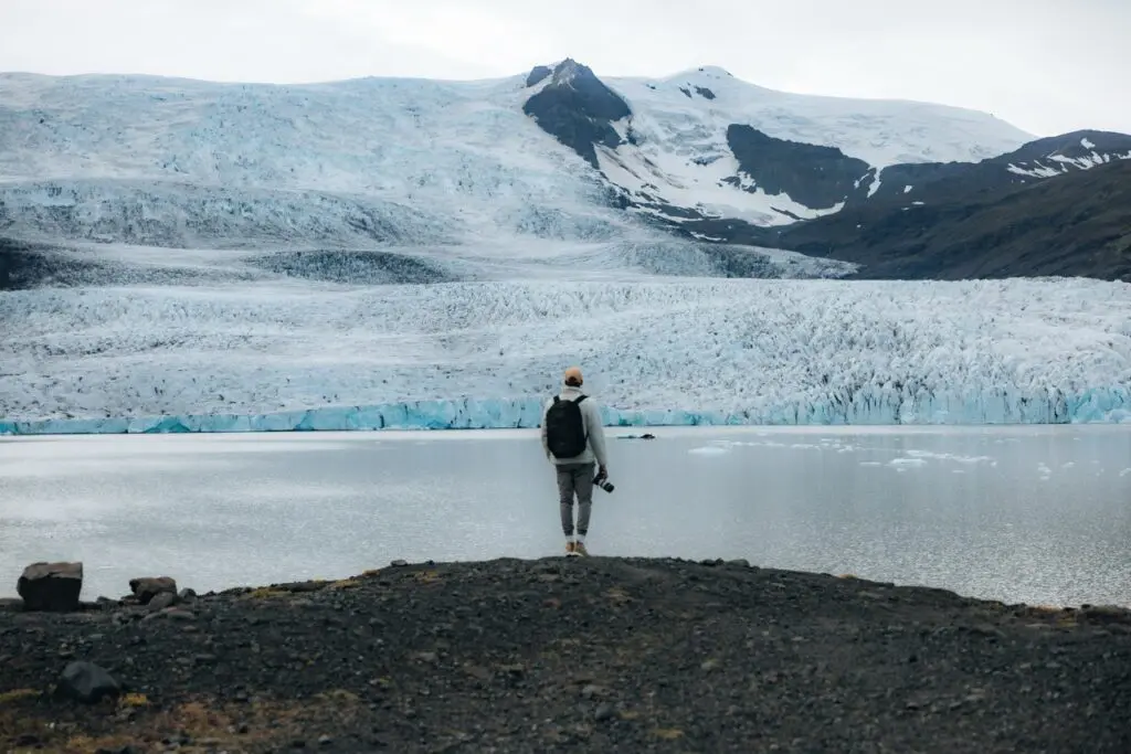 person with camera overlooking a glacier lake in Iceland