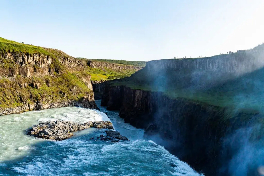 gullfoss waterfall in iceland with tiny people on cliff edge