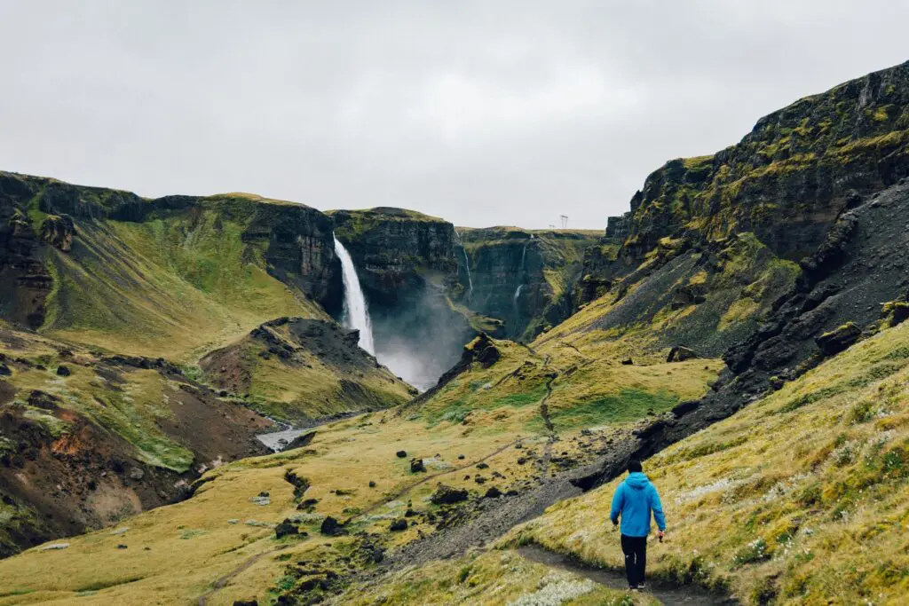 hiker walking towards Haifoss waterfall in Iceland