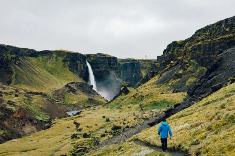 hiker walking towards Haifoss waterfall in Iceland