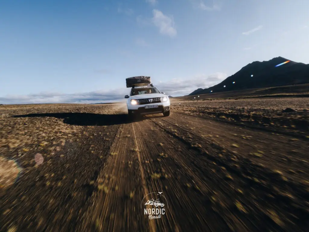 white 4x4 driving on a dirt road in a vast landscape